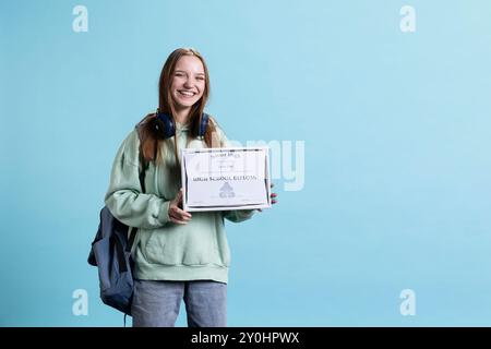 Porträt eines lächelnden Schülers, der ein Highschool-Diplom hält, den Unterricht mit hohen Noten feiert und an der Abschlussfeier teilnimmt. Ein glückliches junges Mädchen freut sich über die Zertifizierung Stockfoto