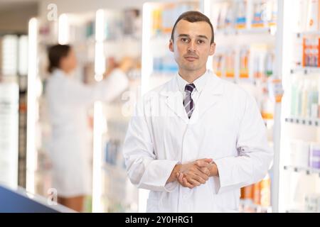 Junger männlicher Apotheker, der Kunden in der Apotheke begrüßt Stockfoto