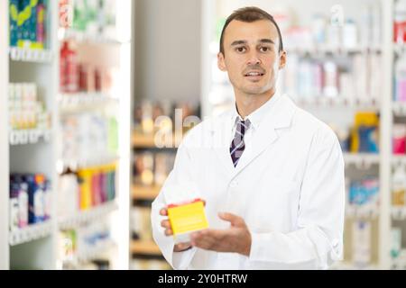 Junger männlicher Apotheker, der die Zubereitung im Karton anbietet Stockfoto