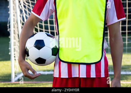 Fußball halten, Spieler in gelber Weste in der Nähe des Tornetzes stehen, Kopierraum Stockfoto