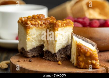 Käsekuchen mit Schokoladenschwammkuchen und Erdnüssen in Karamell, köstliches Dessert mit Erdnüssen und Käsesahne Stockfoto
