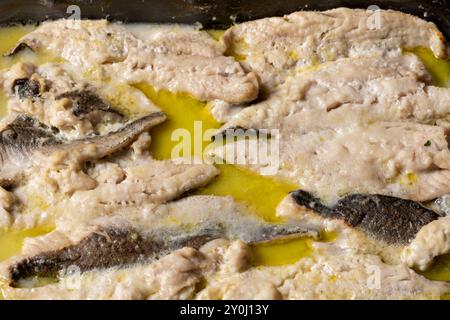 Nahaufnahme von gebackenen Fischfilets in einer reichhaltigen, goldenen Buttersauce, die eine köstliche und herzhafte Mahlzeit bietet, die perfekt für Meeresfrüchte-Liebhaber ist. Stockfoto