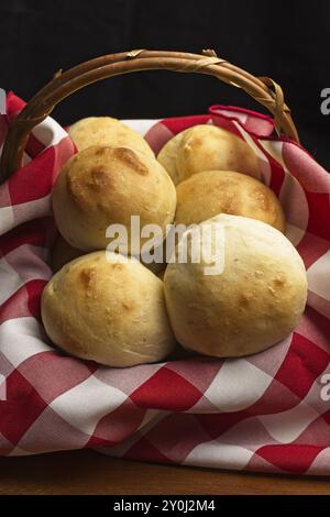 Ein Nahfoto eines kleinen Korbs mit einer rot-weißen Serviette mit gebackenen hausgemachten Dinner Brötchen Stockfoto