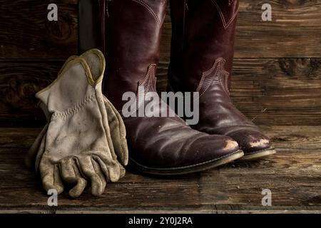 Ein Konzeptbild getragener Cowboystiefel und -Handschuhe Stockfoto