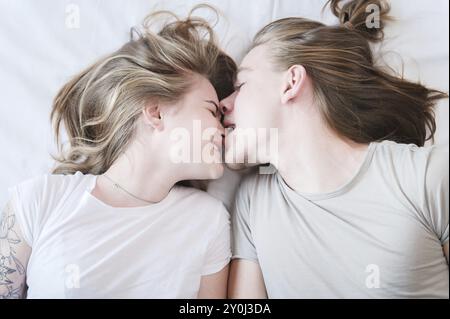 Ein Blick von oben auf ein molo Paar langhaarige Männer und Frauen, die im Bett herumläuften. Ein Mann beißt einem Mädchen an der Nase. Das Konzept eines glücklichen y Stockfoto