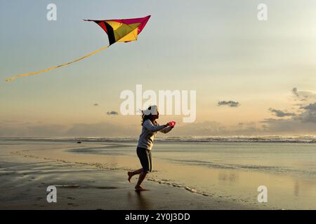 Eine Frau fliegt einen Drachen bei Sonnenuntergang am Strand in Newport, Oregon Stockfoto