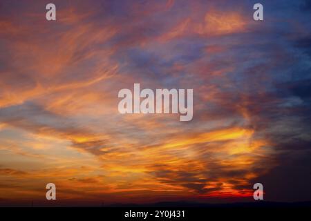 Die untergehende Sonne wirft ein orangefarbenes Leuchten auf die Wolken Stockfoto