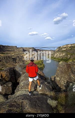 Ein Teenager steht auf einem Felsvorsprung mit Blick auf den majestätischen Snake River und die Perrine Bridge in Twin Falls, Idaho Stockfoto