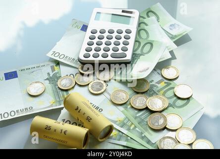 Ein Taschenrechner und Euro-Banknoten neben Münzen, Studio-Aufnahme Stockfoto