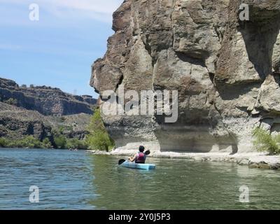 Ein junger Mann im Teenageralter paddelt in der Nähe der felsigen Küste am Snake River in Twin Falls, Idaho Stockfoto