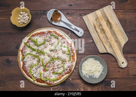 Eine Übersicht über eine ungekochte Wurst und grüne Paprika-Pizza Stockfoto