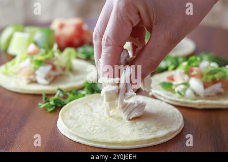 Hühnerstücke auf einen kleinen Straßentako auf ein Holzbrett legen Stockfoto