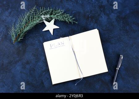 Neujahrsvorsätze, Flachbild-Overhead-Aufnahme mit dem handgeschriebenen Wort Plan und Copyspace, auf dunkelblauem Hintergrund mit einem Stift und einem Weihnachtsornamen Stockfoto