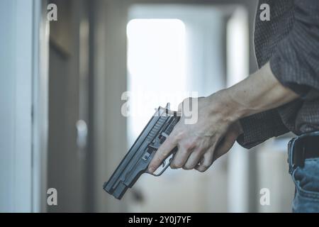 Der Undercover-Polizist hält eine schwarze Waffe in der Hand, bereit zum Schießen Stockfoto