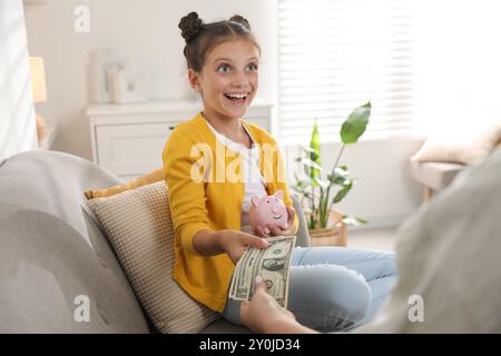 Mutter gibt ihrer Tochter zu Hause Taschengeld Stockfoto