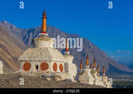 Viele weiße Stupas in einer Reihe auf einem Berg mit blauem Himmel im Hintergrund Stockfoto