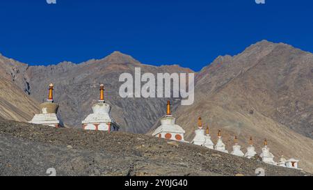 Viele weiße Stupas in einer Reihe auf einem Berg mit blauem Himmel im Hintergrund Stockfoto