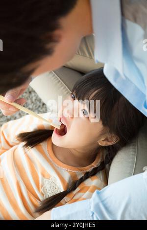 Vater hilft einem Mädchen, sich die Zähne zu putzen Stockfoto