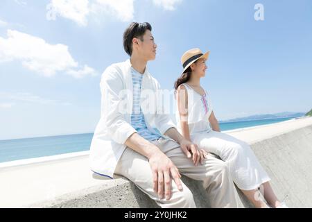 Pärchen sitzen auf dem Wellenbrecher Stockfoto