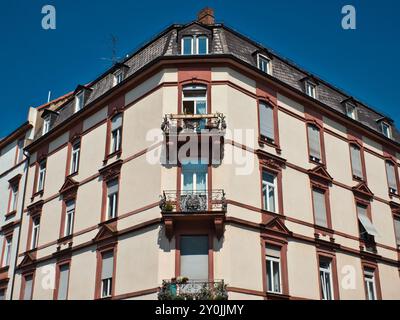 Ein Bild eines historischen Gebäudes mit einem Balkon an der Ecke an der weißen Fassade und wunderschön dekorierten Fenstern Stockfoto