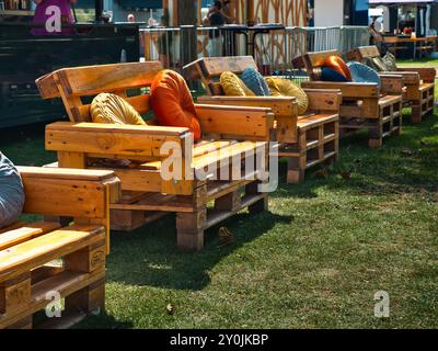 Sitzplätze aus Paletten, mit bunten Kissen auf einem grünen Bereich und Stadtfest Stockfoto