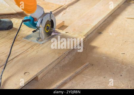 Holzsperrholz wird vom Arbeiter mit einer Kreissäge geschnitten Stockfoto