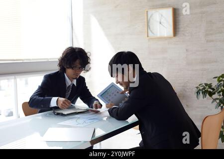 Zwei Geschäftsleute, die einen Termin haben, während sie sich ein Tablet ansehen Stockfoto