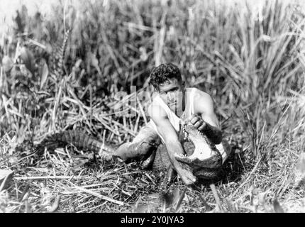 Henry Charles 'Alligator Boy' Coppinger Jr. (1898–1975) mit einem gefangenen Alligator am 28. Januar 1921 in der Gegend um Miami River in Südflorida. Coppinger „erfand“ das Alligatorwrestling und lehrte es den Seminolen-Indianern, die das Ritual Anfang des 20. Jahrhunderts zu einer Attraktion für Touristen machten. (USA) Stockfoto