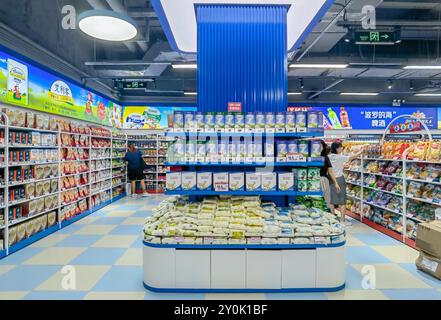 Shenzhen, China - 2. September 2024 : Ein gut beleuchteter Supermarktgang in Shenzhen, China, mit verschiedenen Lebensmittelprodukten in Regalen, mit einer Ausstellung von Stockfoto