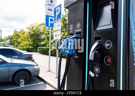 Stromversorgung für das Aufladen von Elektroautos. Ladestation für Elektroautos. Nahaufnahme der Stromversorgung und des aufladenden Elektroautos. Stockfoto