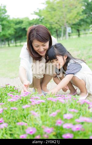 Mutter und Tochter sitzen vor dem Blumenbeet Stockfoto