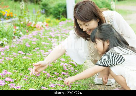 Mutter und Tochter sitzen vor dem Blumenbeet Stockfoto