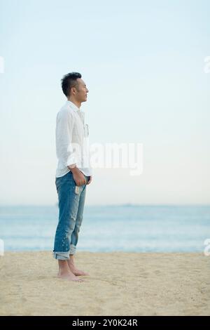 Japanischer Mann, der am Strand steht Stockfoto