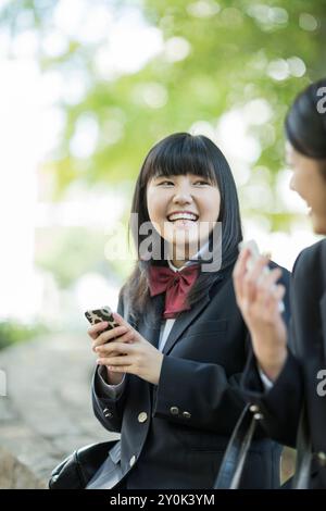 Highschool-Mädchen, die sich auf einem Handy unterhalten Stockfoto