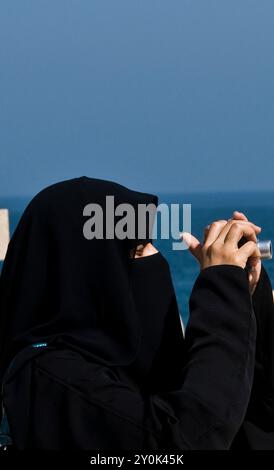 Eine ägyptische Frau, die ein Foto durch ihren schwarzen Schleier macht. Fort Qaitbey, Alexandria, Ägypten. Stockfoto