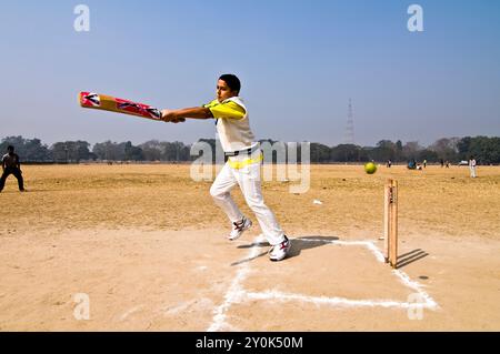 Ein Junge, der mit seinen Freunden Cricket spielt, im Maidan in Kalkutta, Westbengalen, Indien. Stockfoto