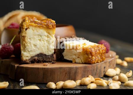 Käsekuchen mit Schokoladenschwammkuchen und Erdnüssen in Karamell, köstliches Dessert mit Erdnüssen und Käsesahne Stockfoto