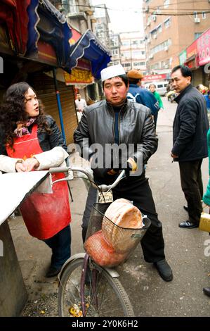 Ein muslimischer Mann kauft frisches Brot in einer lokalen Bäckerei im Xinjiang-Stil in den Straßen von Nanjing, China. Stockfoto