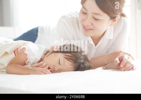 Mutter schaut sanft auf ein Baby und macht ein Nickerchen Stockfoto