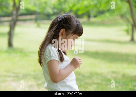 Mädchen, das Löwenzahn-Flaum bläst Stockfoto