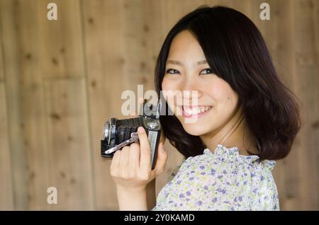 Frau lächelt und hält eine alte Kamera Stockfoto