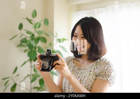 Lächelnde Frau, die auf eine alte Kamera blickt Stockfoto