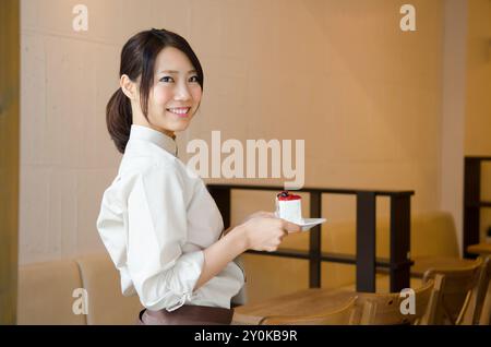 Der Ladenassistent eines Cafés mit einem Kuchen Stockfoto