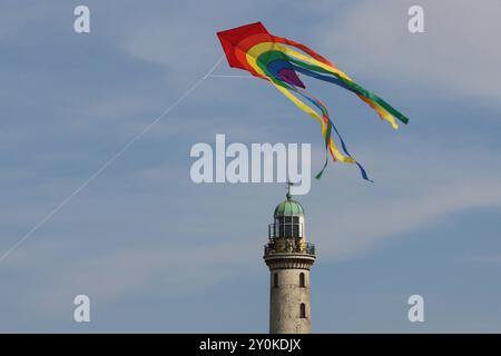 Blick am Mittwoch 14.08.2024 im Ostseebad Warnemünde, ein Ortsteil der Hanse- und Universitätsstadt Rostock, bei sommerlichem Wetter auf den historischen Leuchtturm während davor ein Tourist einen Drachen steigen lässt. In den Urlaubsorten entlang der Ostseeküste des Landes Mecklenburg Vorpommern herrscht derzeit reges Treiben. In direkter Strandnähe ist fast kein freier Platz mehr zu finden und die Restaurants sind gut besucht. Dennoch bleibt ein Wermutstropfen. Die Preise in den Tourismusregionen des Landes MV sind in diesem Jahr noch einmal gestiegen. Das hält zahlreiche Menschen aber nic Stockfoto