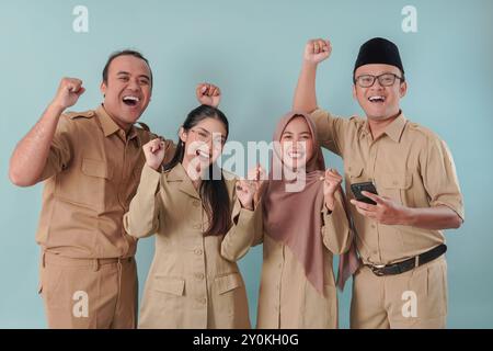 Vier indonesische Regierungsangestellte in khakifarbener Uniform lächelten mit einem glücklichen, erfolgreichen Ausdruck in die Kamera. PNS und Beamtenkonzept. Stockfoto