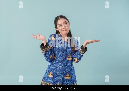 Verwirrte Regierungsangestellte in blauer Batikuniform und Brille, die auf den Kopierraum neben ihr zeigt, wählte die Option. PNS-Konzept. Stockfoto