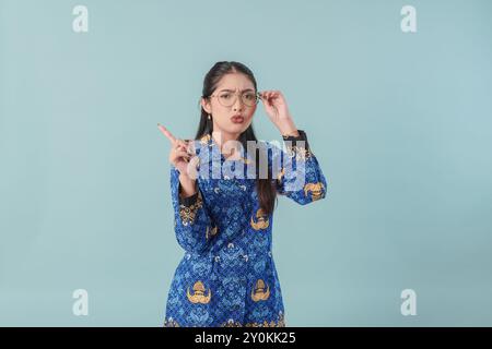 Durchdachte Regierungsangestellte in blauer Batikuniform und Brille, die auf den Kopierraum neben ihr zeigt. PNS-Beamtenkonzept. Stockfoto