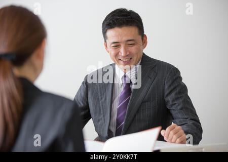 Geschäftsmann mittleren Alters in seinen 40ern, der mit weiblichen Angestellten spricht Stockfoto