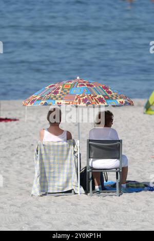 Zwei Rentner sitzen am Donnerstag 29.08.2024 im Ostseeheilbad Zingst Landkreis Vorpommern Rügen am örtlichen Strand unter einem Sonnenschirm. In Mecklenburg Vorpommern herrscht im Verlauf des Tages hochsommerliche Temperaturen. Sie lockten erneut zahlreiche einheimische und Touristen an die Strände entlang der Ostseeküste und der Seenplatte. Passend dazu stellt am Nachmittag der Minister für Wirtschaft, Infrastruktur, Tourismus und Arbeit Reinhard Meyer mit weiteren Persönlichkeiten im Rahmen einer Pressekonferenz die touristische Saisonbilanz vor. *** Zwei Rentner sitzen unter einem Sonnenschirm auf t Stockfoto