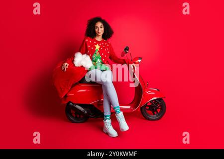 Foto von reizenden charmanten niedlichen Mädchen tragen Pullover Neujahrsvorbereitung Geschenke Magie Zeit isoliert auf rotem Hintergrund Stockfoto